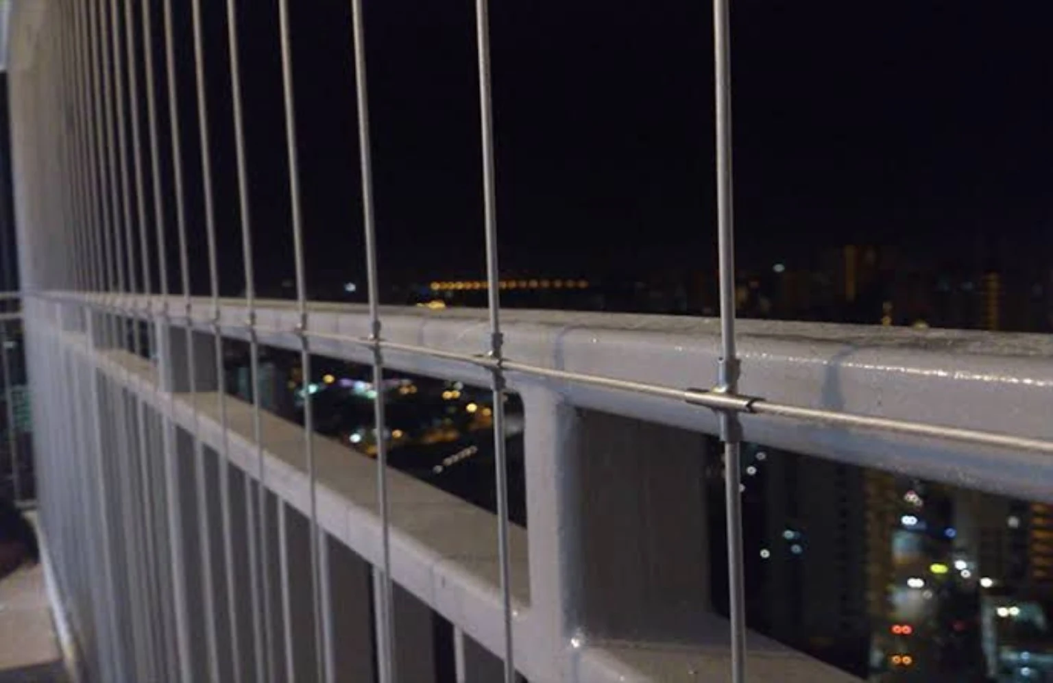 Invisible stainless steel cables installed across a high-rise balcony at night