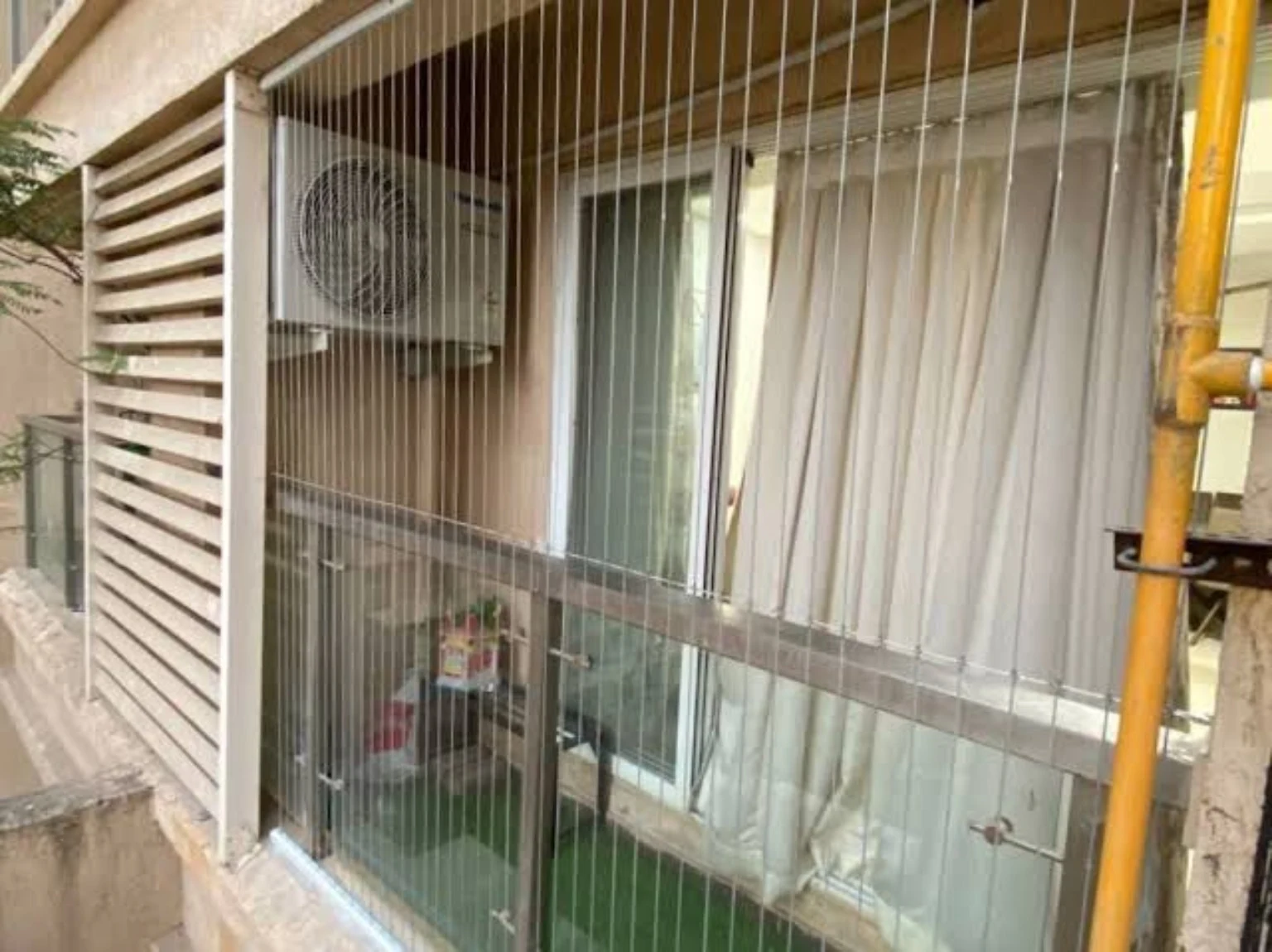 Vertical stainless steel safety cables installed across a residential window and balcony opening